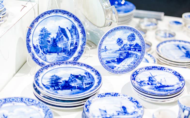 Royal Delft Blue pottery plates with scenic designs on display.