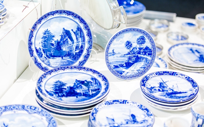 Royal Delft Blue pottery plates with scenic designs on display.