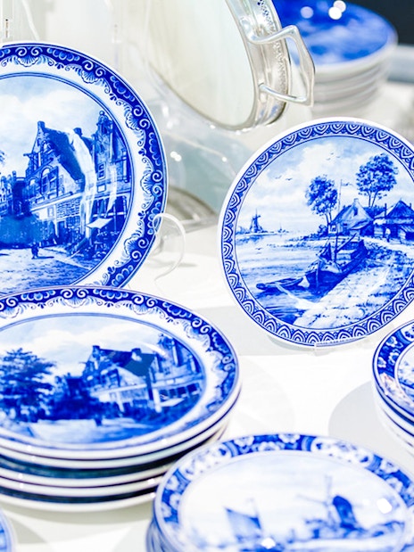 Royal Delft Blue pottery plates with scenic designs on display.