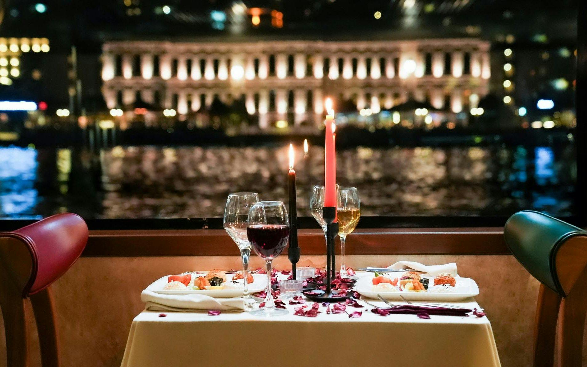 Dinner table with wine and candles on a Bosphorus cruise, Istanbul skyline in background.