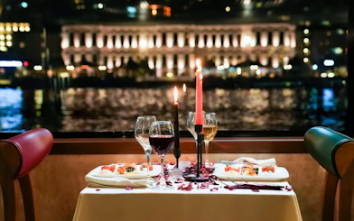 Dinner table with wine and candles on a Bosphorus cruise, Istanbul skyline in background.