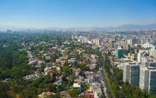 Aerial view of Mexico City neighborhoods with buildings and greenery.
