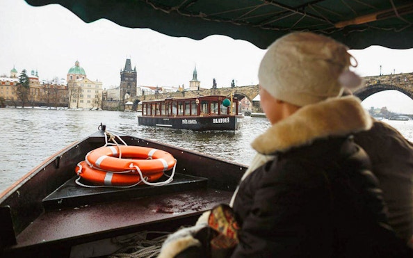 Prague river cruise with view of Charles Bridge and historic buildings.