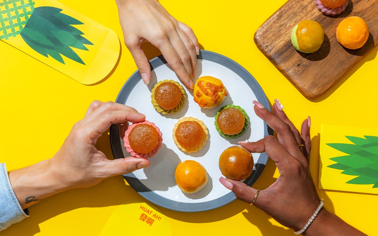 Hands reaching for traditional pastries on a plate, Singapore Cable Car Sky Pass.