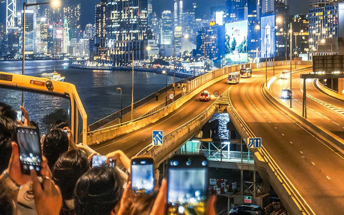 Open-top bus tour in Hong Kong capturing city skyline and highway at night.