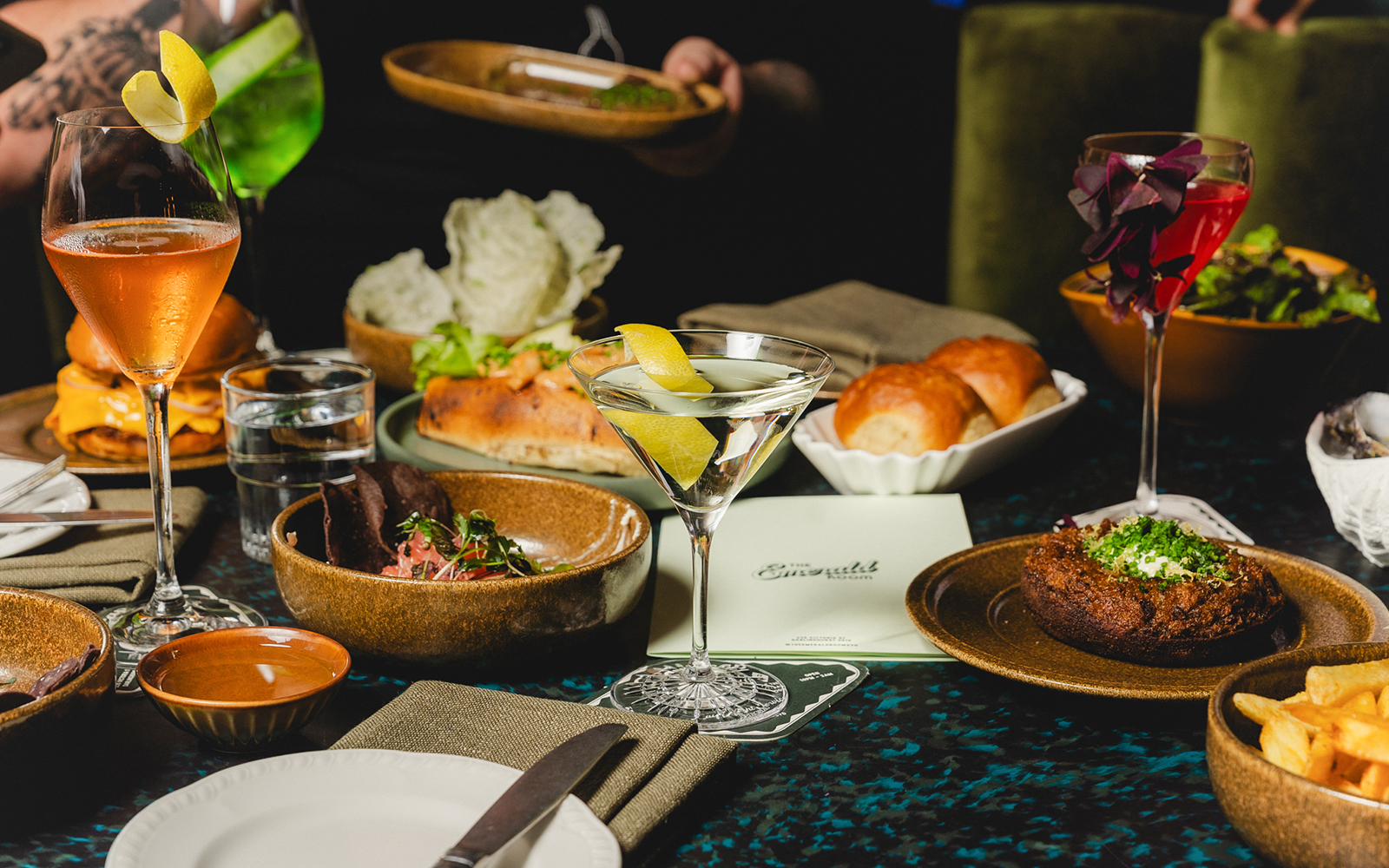 Elegant dining setup with cocktails and gourmet dishes at The Emerald Room party.