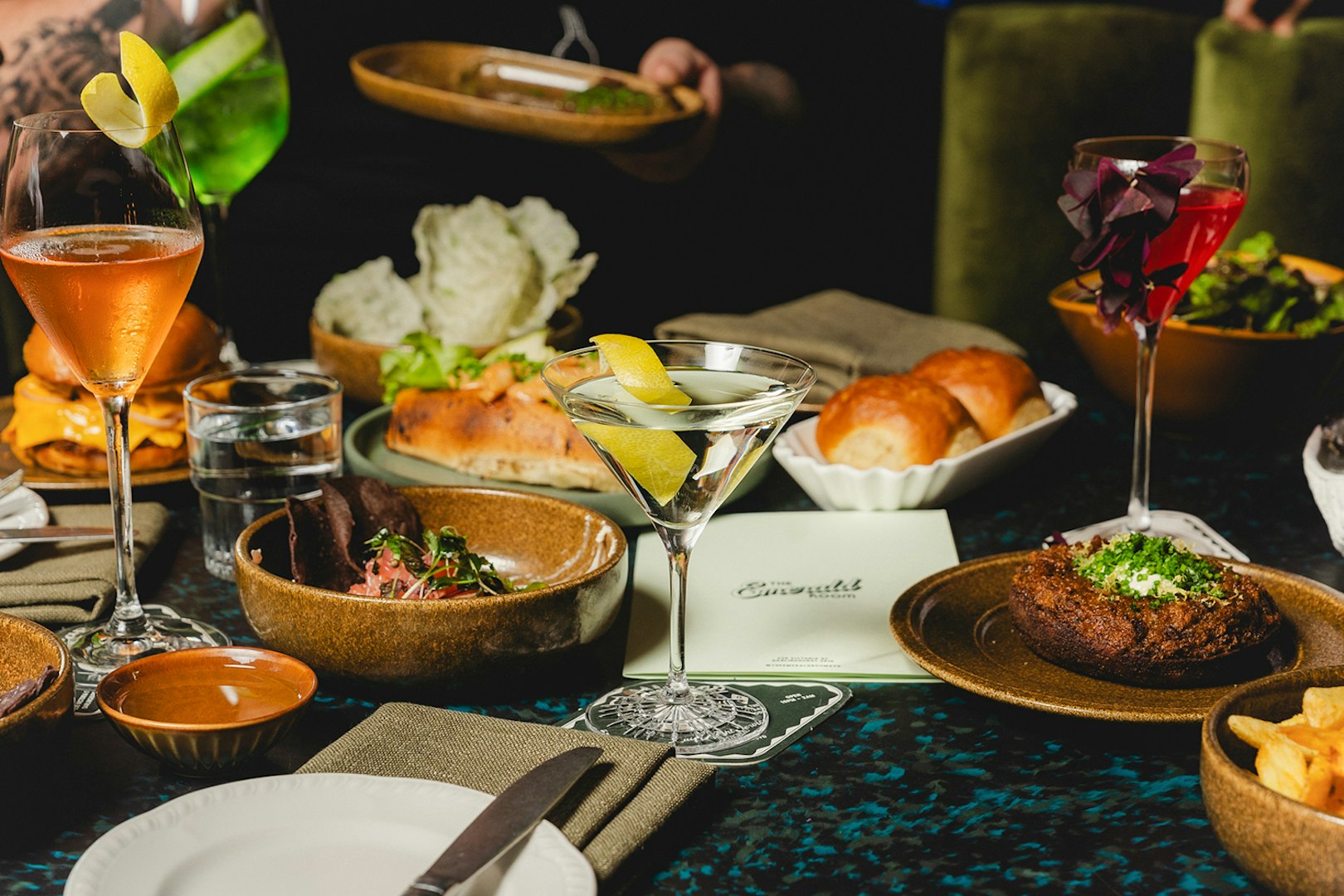 Elegant dining setup with cocktails and gourmet dishes at The Emerald Room party.