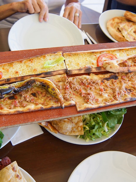 Turkish pide served on a wooden board during Antalya sightseeing city tour.