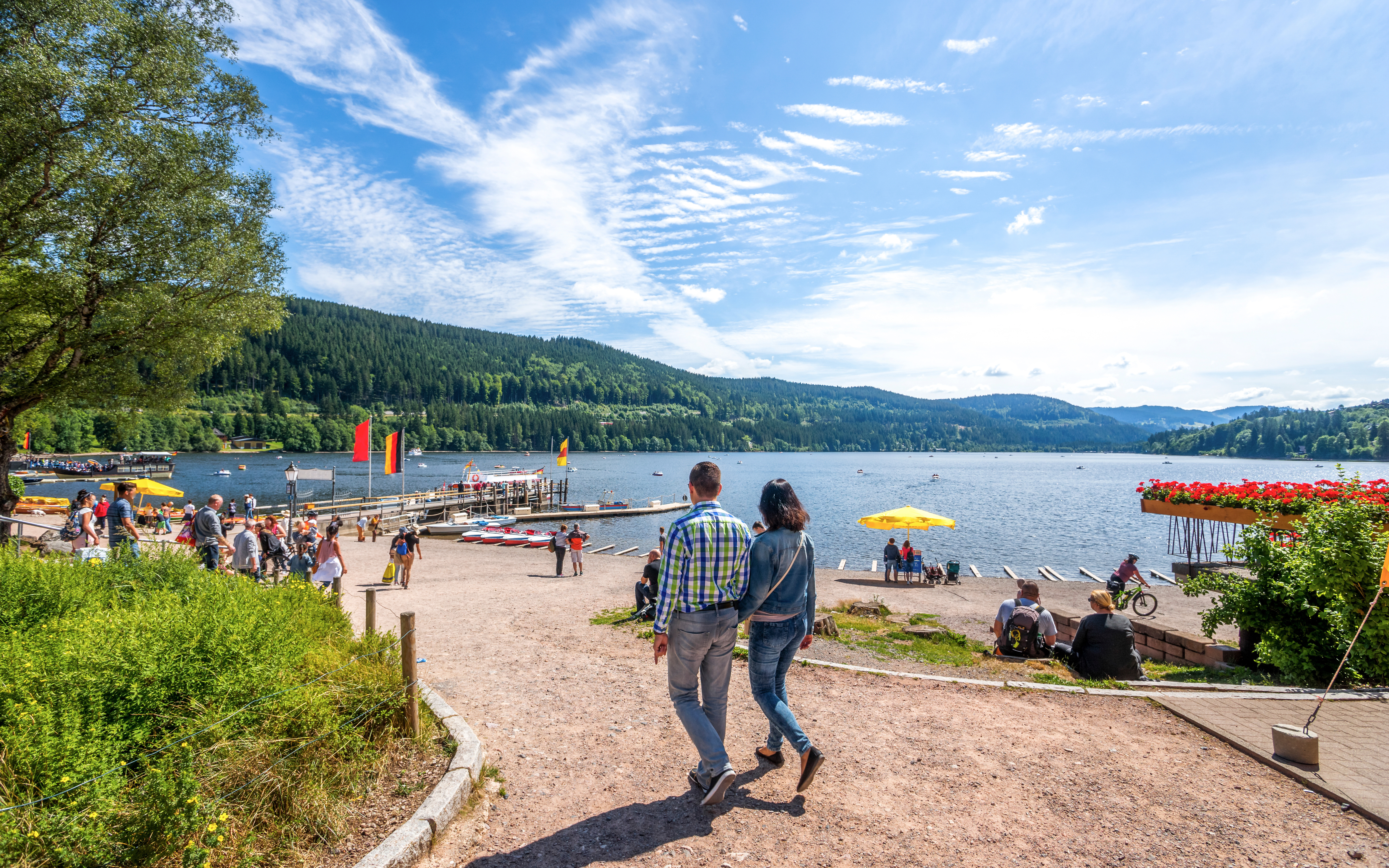 Couple walking along Lake Titisee with scenic view of Black Forest in Germany.