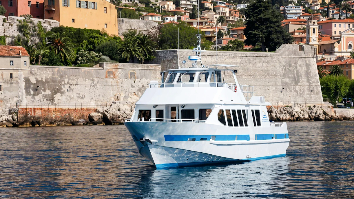 Boat cruising near Villefranche-sur-Mer with colorful hillside buildings in the background.