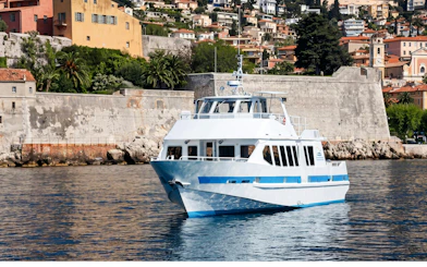 Boat cruising near Villefranche-sur-Mer with colorful hillside buildings in the background.