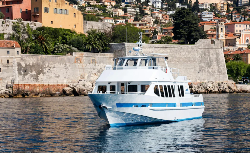Boat cruising near Villefranche-sur-Mer with colorful hillside buildings in the background.