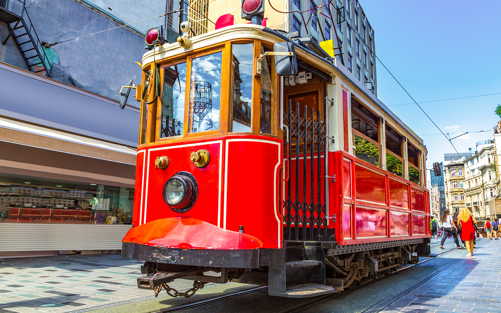 Retro tram on Istiklal Avenue, Istanbul, with pedestrians and shops nearby.