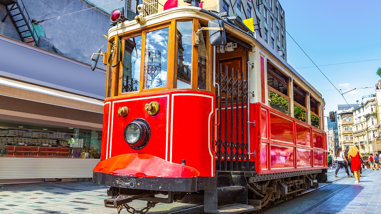 Retro tram on Istiklal Avenue, Istanbul, with pedestrians and shops nearby.
