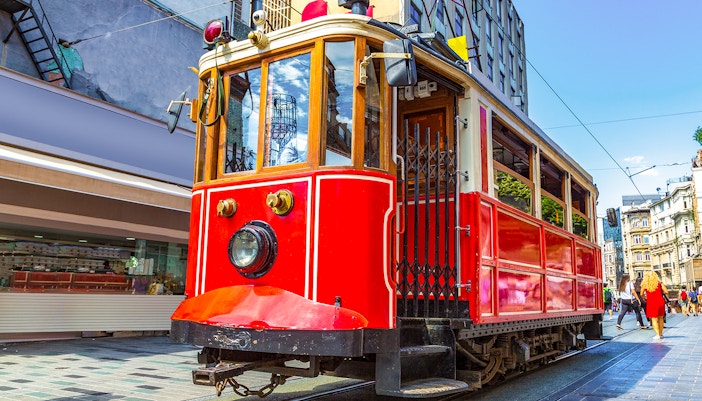 Retro tram on Istiklal Avenue, Istanbul, with pedestrians and shops nearby.