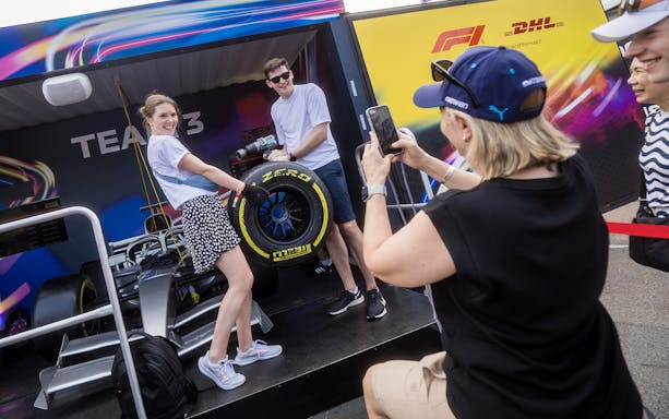 Participants in a pit stop challenge at F1 Singapore, changing a tire on a race car.