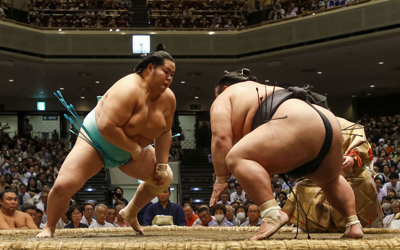 Sumo wrestlers competing in a traditional match in a crowded arena.