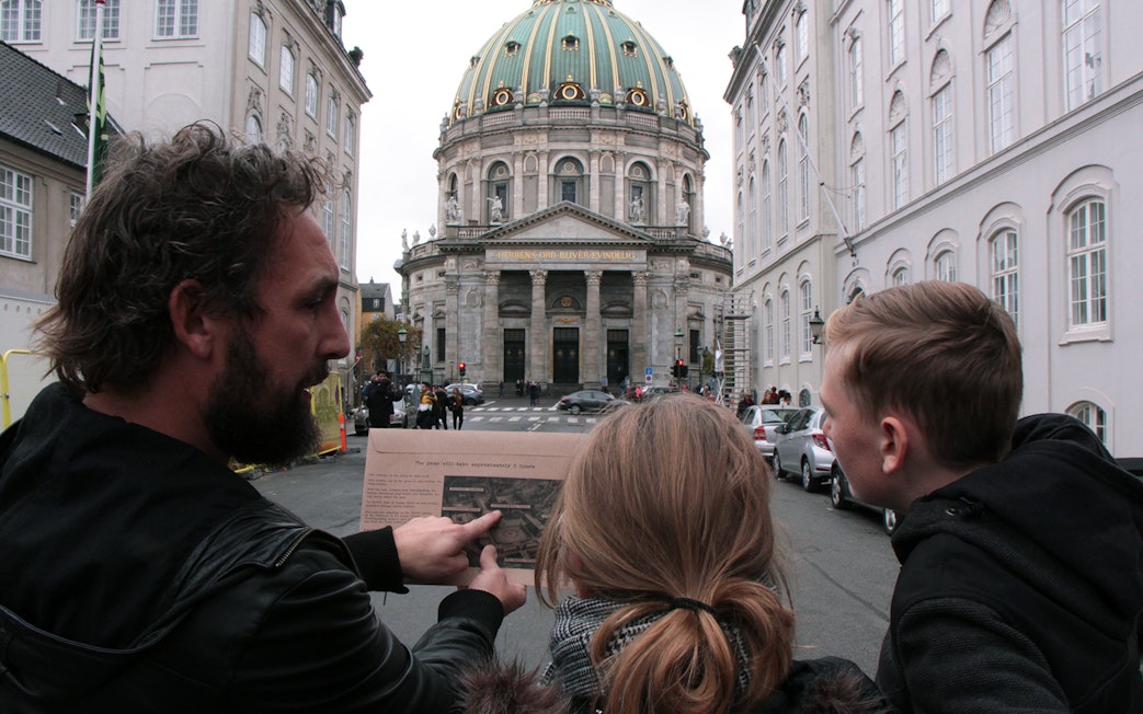 Participants in a mystery hunt near Amalienborg Palace, Copenhagen, examining a map.