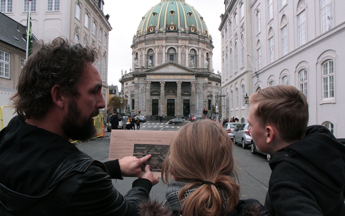 Participants in a mystery hunt near Amalienborg Palace, Copenhagen, examining a map.