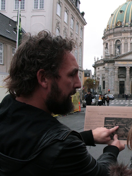 Participants in a mystery hunt near Amalienborg Palace, Copenhagen, examining a map.