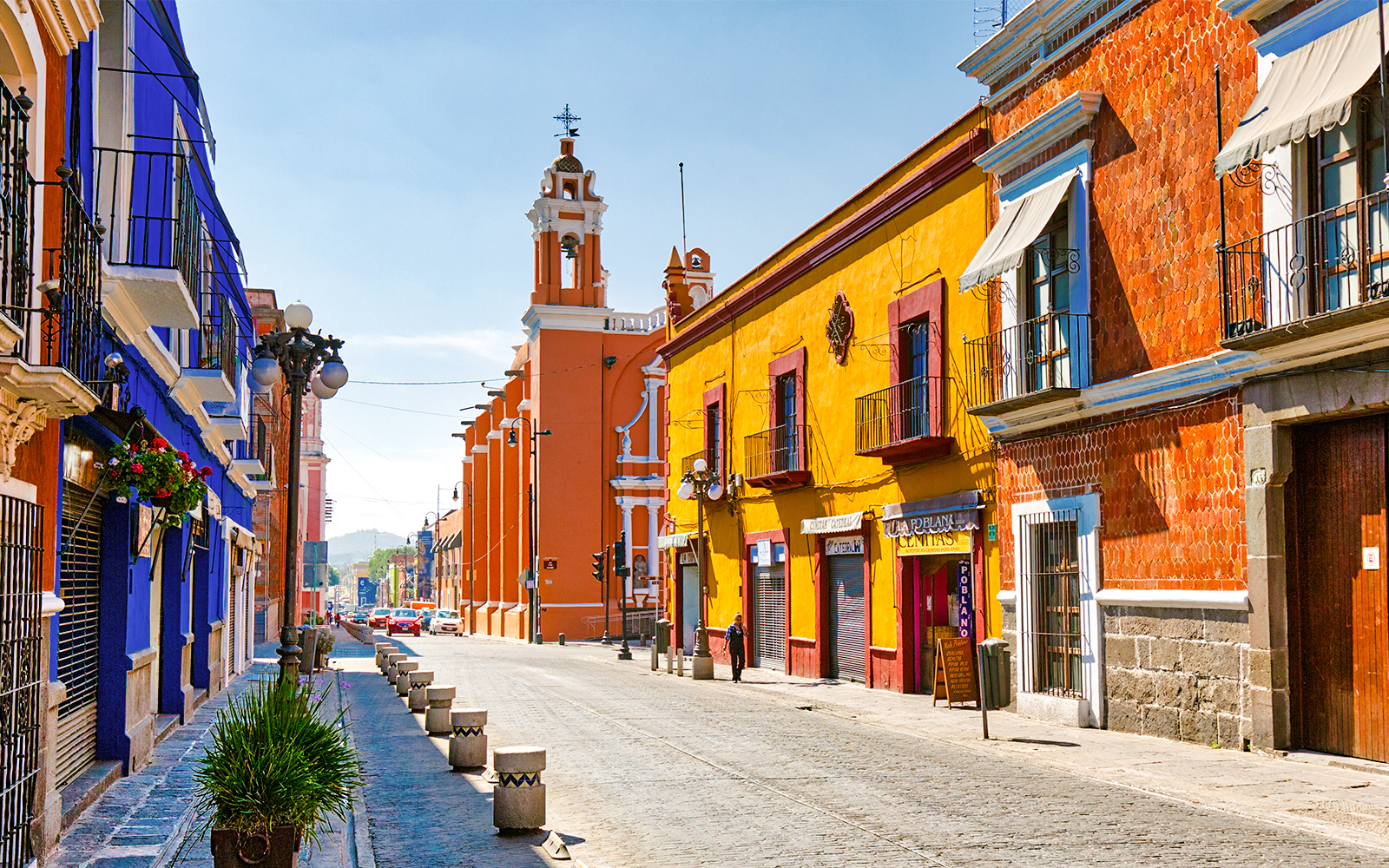 Colorful buildings along cobblestone street in historic Mexico City center.