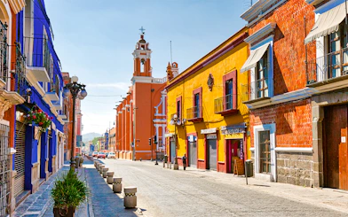 Colorful buildings along cobblestone street in historic Mexico City center.