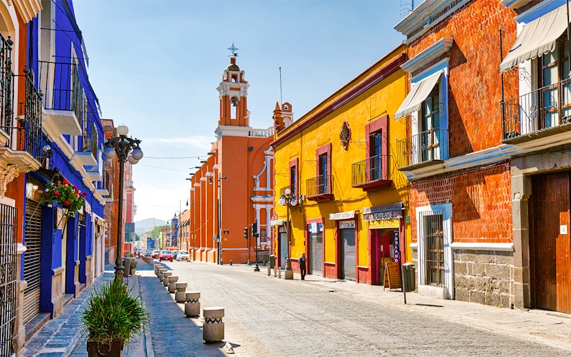 Colorful buildings along cobblestone street in historic Mexico City center.