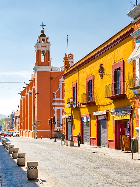 Colorful buildings along cobblestone street in historic Mexico City center.