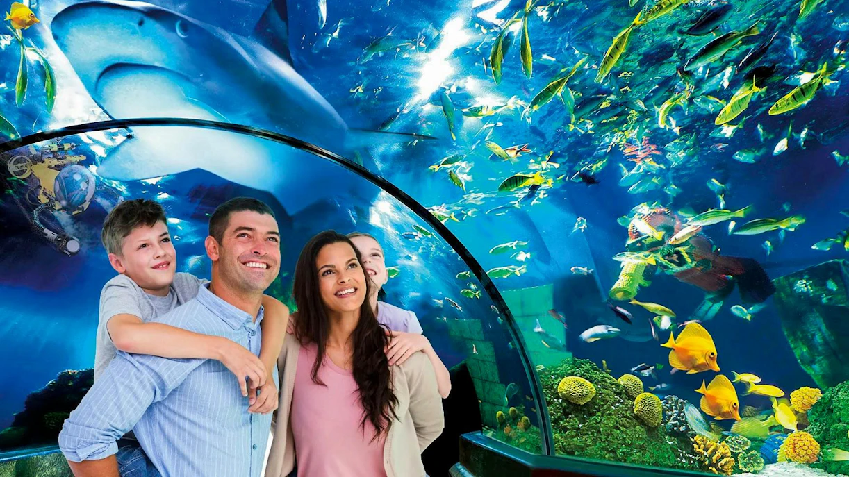 Family exploring underwater tunnel at Atlantis, LEGOLAND® Billund with fish and shark overhead.