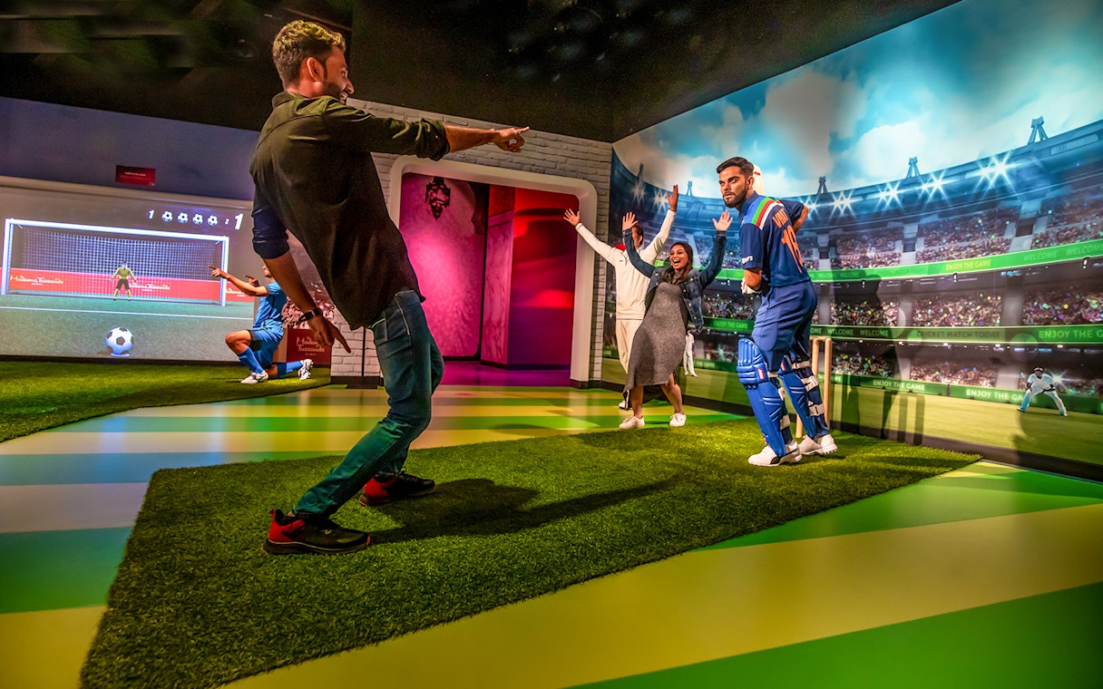Visitors interacting with a cricket player wax figure at Dubai Madame Tussauds.