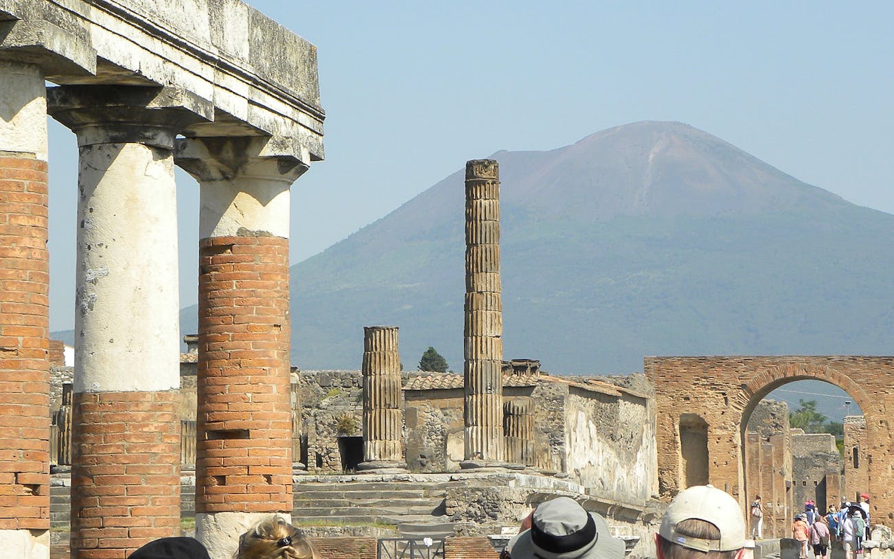 Ancient ruins of Pompeii with Mount Vesuvius in the background, part of a tour from Rome.
