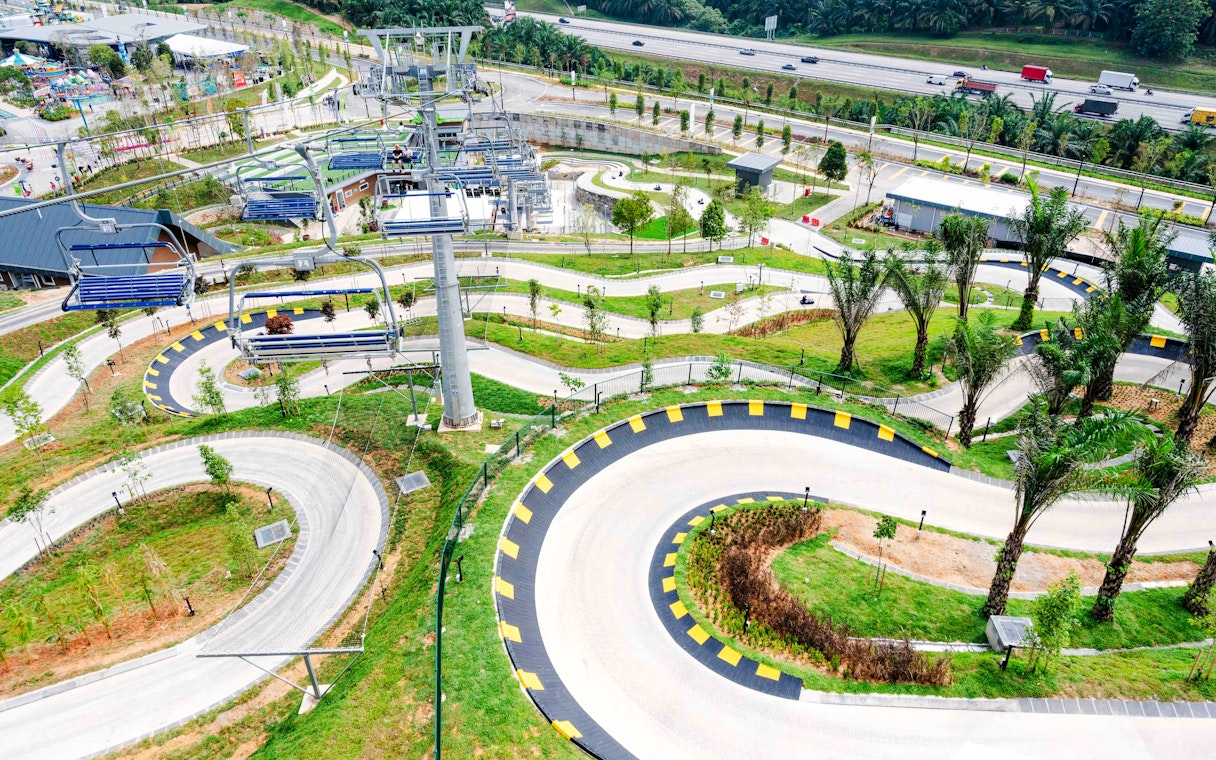 Skyline Luge track with winding paths and chairlift in lush green landscape.