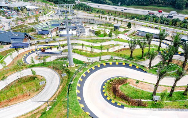 Skyline Luge track with winding paths and chairlift in lush green landscape.