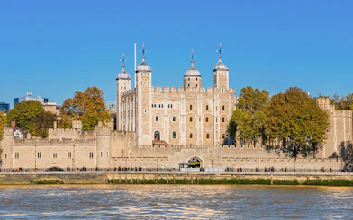 Tower of London exterior with river view and surrounding trees.