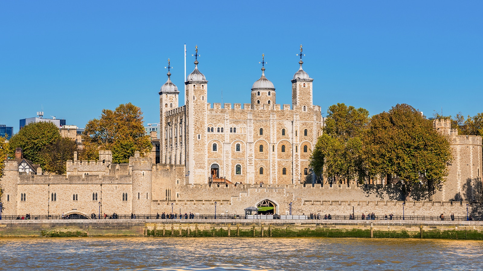 Tower of London exterior with river view and surrounding trees.