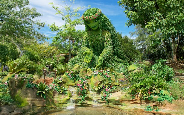 Giant green sculpture inspired by Moana surrounded by lush plants at Walt Disney Resort Orlando.