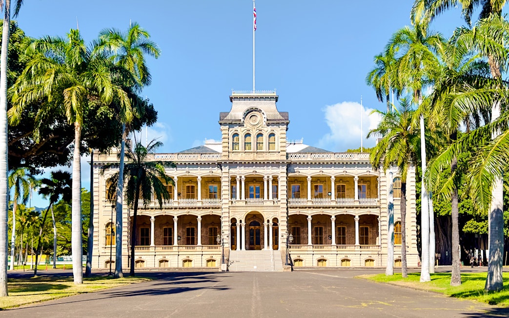 Iolani Palace with palm trees in lush gardens, Honolulu, Hawaii.