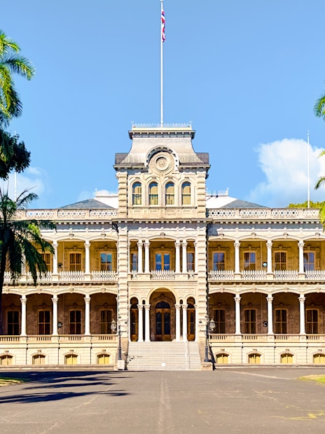 Iolani Palace with palm trees in lush gardens, Honolulu, Hawaii.