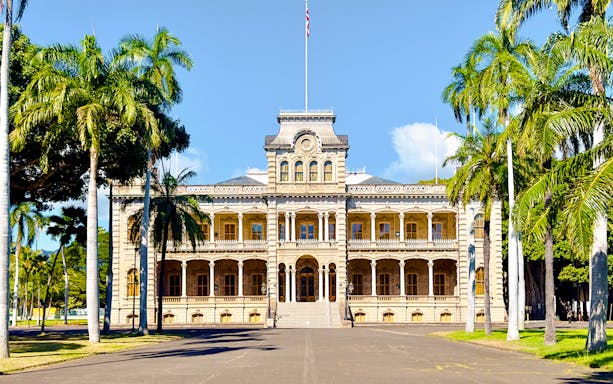 Iolani Palace with palm trees in lush gardens, Honolulu, Hawaii.