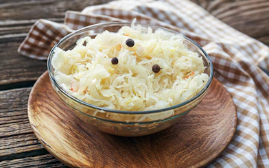 Bowl of sauerkraut with peppercorns on a wooden table, Kraków Street Food Tour.