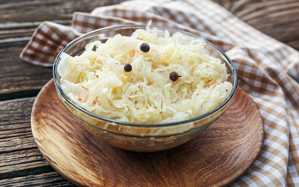 Bowl of sauerkraut with peppercorns on a wooden table, Kraków Street Food Tour.