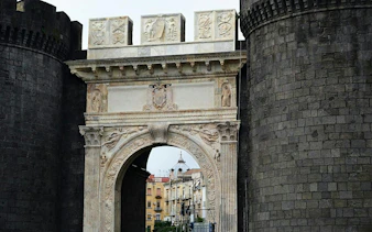 Medieval stone archway at Castel Nuovo, Naples, part of a self-guided city exploration game.