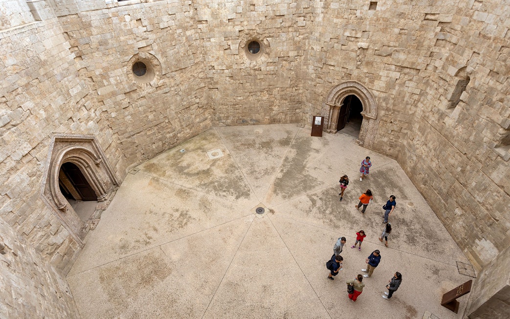 Tour group with guide inside Castel del Monte courtyard, Andria.