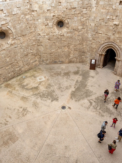 Tour group with guide inside Castel del Monte courtyard, Andria.