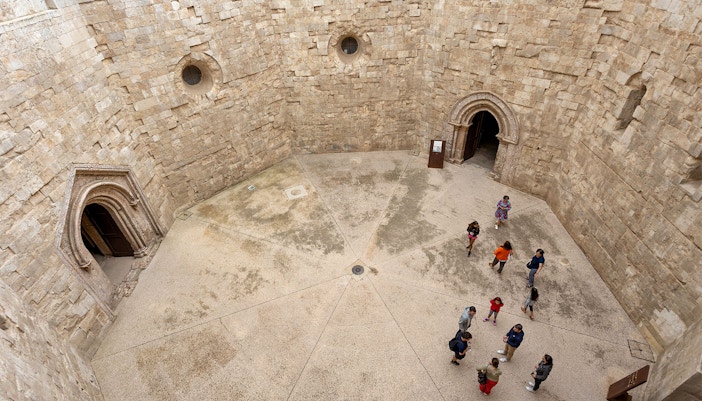 Tour group with guide exploring Castel del Monte, Andria, Italy.