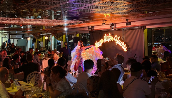 Belly dancer performing on a Bosphorus dinner cruise with guests seated at private tables.