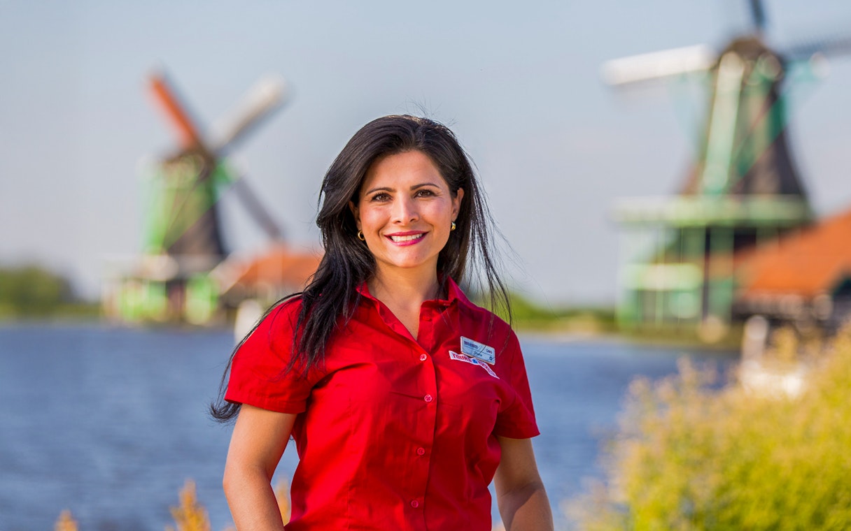 Tour guide at Zaanse Schans with windmills in the background, Netherlands.