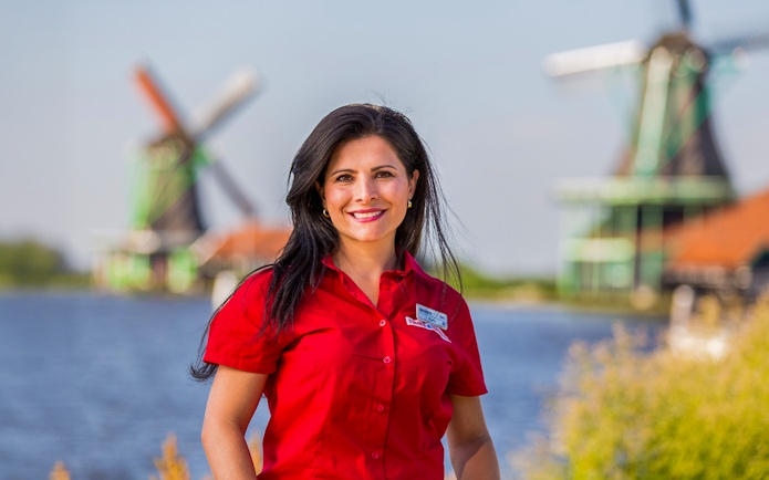 Tour guide at Zaanse Schans with windmills in the background, Netherlands.