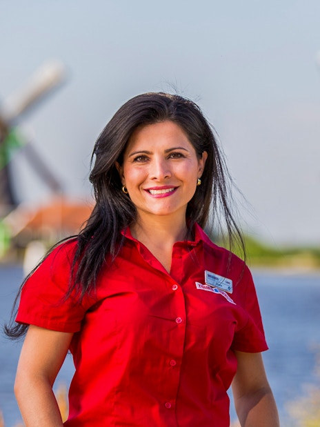 Tour guide at Zaanse Schans with windmills in the background, Netherlands.