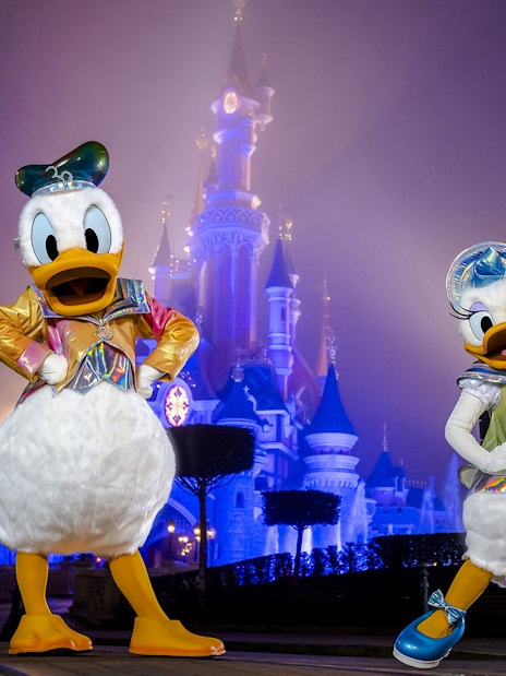 Disney characters in front of Sleeping Beauty Castle at Disneyland Paris.